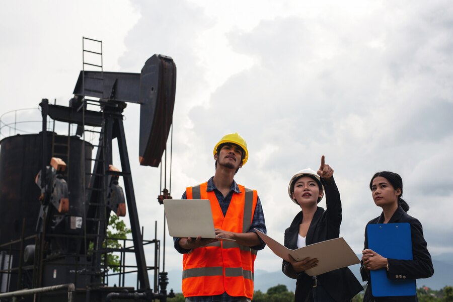 engineering team stands beside working oil pumps with sky 1150 19223